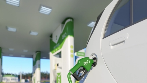 Close-up of a green fuel nozzle marked BIO connected to a white vehicle at a biofuel filling station